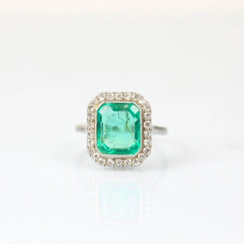 255 - An early 20th century untested emerald and diamond cluster ring, the central emerald cut emerald wit... 