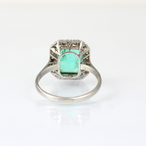 255 - An early 20th century untested emerald and diamond cluster ring, the central emerald cut emerald wit... 