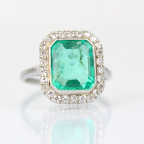 255 - An early 20th century untested emerald and diamond cluster ring, the central emerald cut emerald wit... 