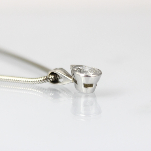 284 - A diamond solitaire pendant, the pear cut diamond within a white metal rubover mount, indistinctly s... 