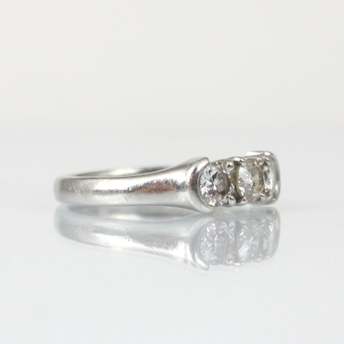 323 - An 18ct white gold diamond three stone ring, the three round cut diamonds within claw and rub over s... 