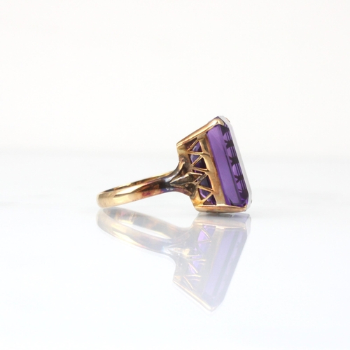 332 - An untested amethyst cocktail ring, the emerald cut untested amethyst within claw setting edge, lead... 