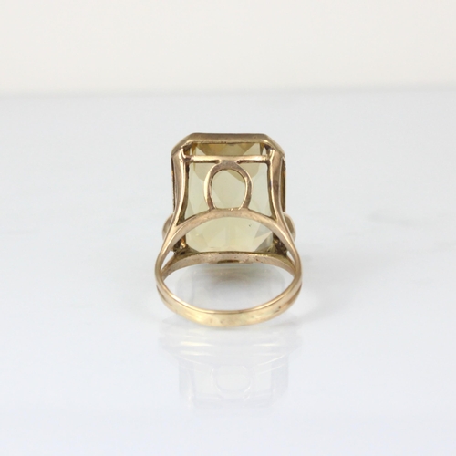 339 - An early 20th century citrine cocktail ring, the emerald cut stone within gold coloured rub over mou... 