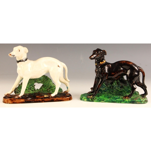 569 - Two French majolica greyhounds, 19th century, each modelled standing against a rough bocage support ... 