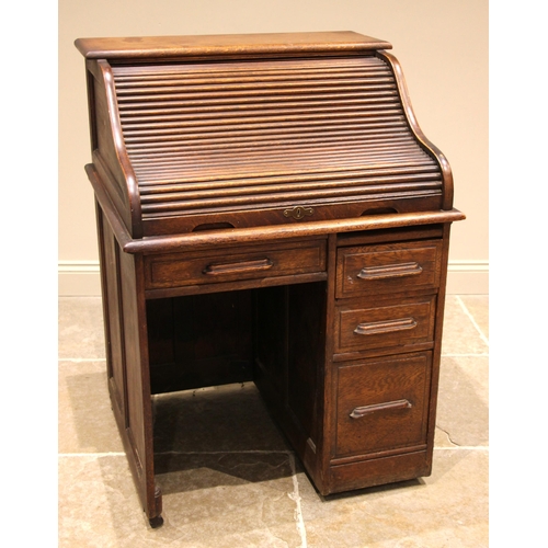 1001 - An early 20th century oak roll top desk, the tambour front opening to a compartmented interior over ... 