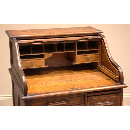 1001 - An early 20th century oak roll top desk, the tambour front opening to a compartmented interior over ... 