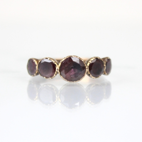 263 - A late 19th century flat cut 'garnet' ring, the five foil backed stones leading to engraved shoulder... 