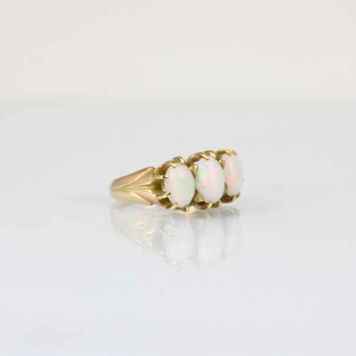 266 - A three stone opal ring, the three graduated oval cabochons within yellow metal claw setting edge le... 