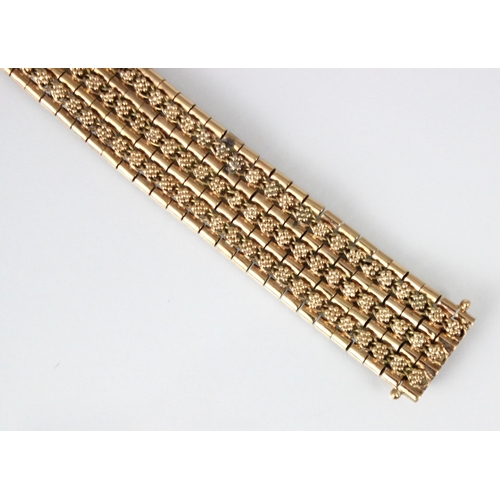 270 - A late 20th century yellow metal bracelet, the wide bracelet with stylised floral repeating decorati... 