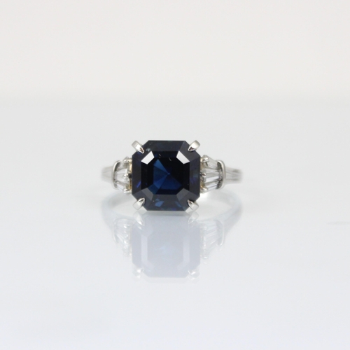 316 - An Art Deco style diamond and untested sapphire ring, the central emerald cut untested sapphire claw... 