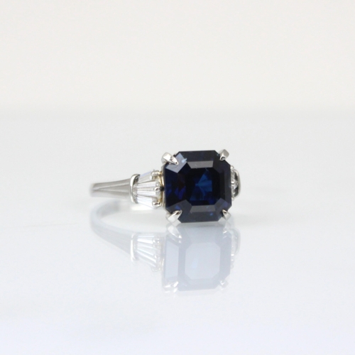 316 - An Art Deco style diamond and untested sapphire ring, the central emerald cut untested sapphire claw... 