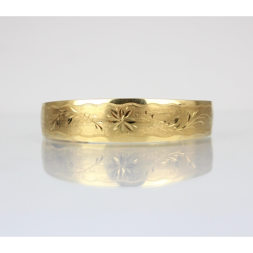 352 - A Bucherer yellow metal bangle, the tapered bangle with engraved floral decoration to front, stamped... 