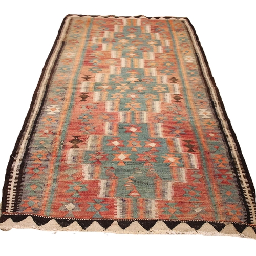 801 - A flat weave kilim rug, in red, green and brown colourways, the central red field with three linked ... 