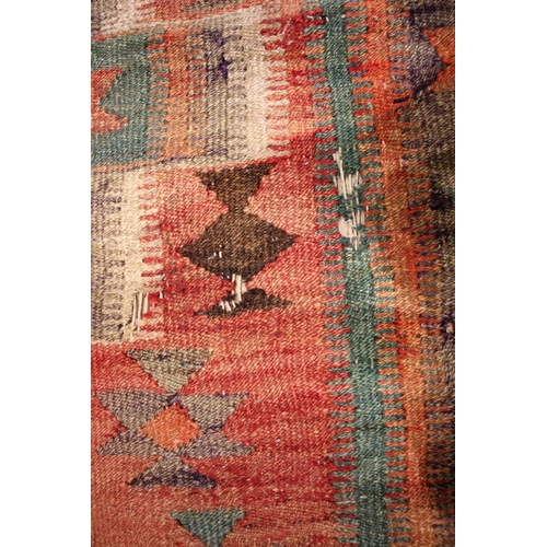 801 - A flat weave kilim rug, in red, green and brown colourways, the central red field with three linked ... 