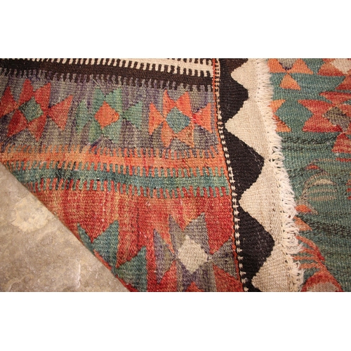 801 - A flat weave kilim rug, in red, green and brown colourways, the central red field with three linked ... 