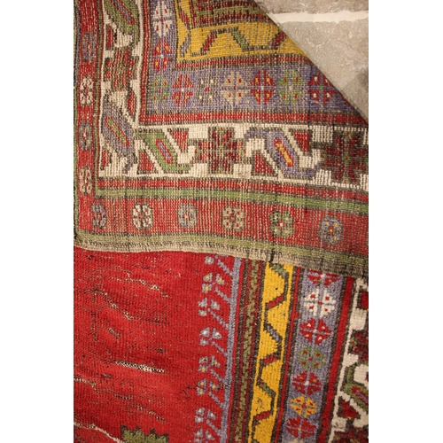 805 - A Turkish hand knotted village rug, the central vibrant red field with a stylised leaf motif enclose... 