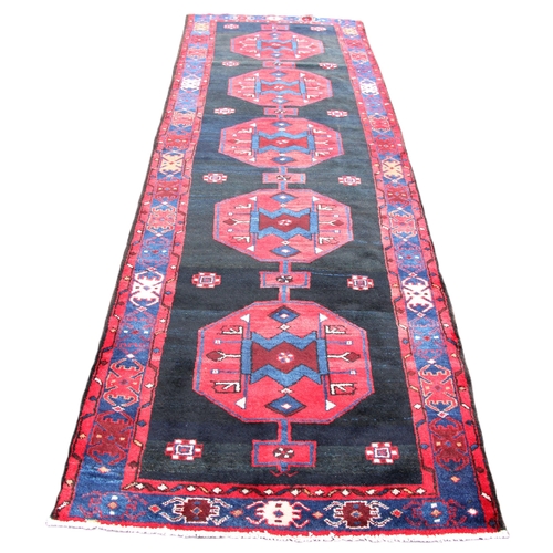 813 - A deep ground full pile hand woven Persian Nahvand runner, the central field with five linked octago... 