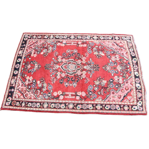 814 - A washed red ground hand woven Persian Sarouk village rug, centred with a floral medallion, 196cm x ... 