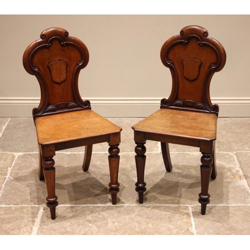 950 - A pair of Victorian mahogany hall chairs, each with a 'C' scroll moulded, trefoil back rest centred ... 