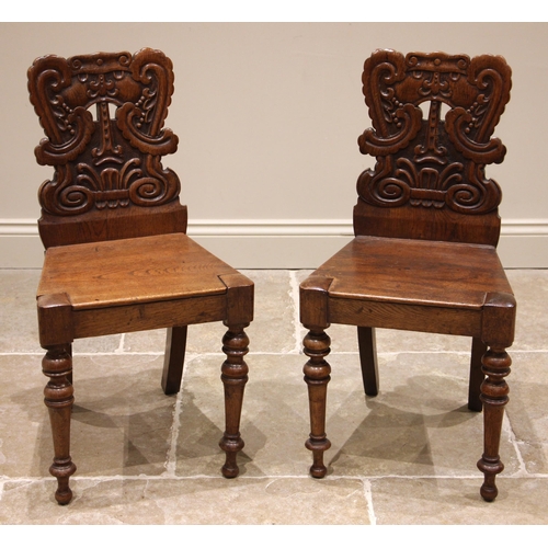 956 - A pair of 19th century oak hall chairs, each with a scrolled and interlaced back rest, over a board ... 