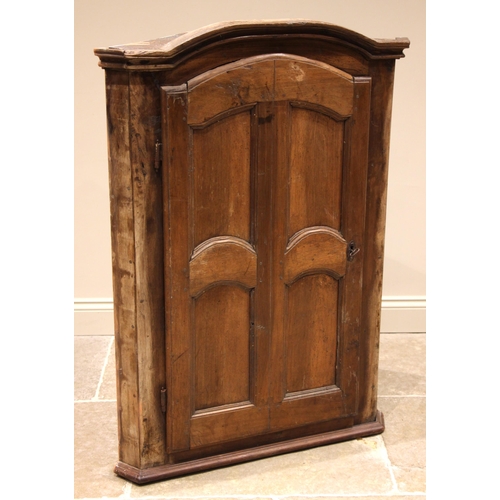 962 - A 19th century rustic French hanging corner cupboard, probably fruitwood, the moulded and arched cor... 