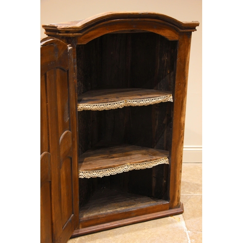 962 - A 19th century rustic French hanging corner cupboard, probably fruitwood, the moulded and arched cor... 