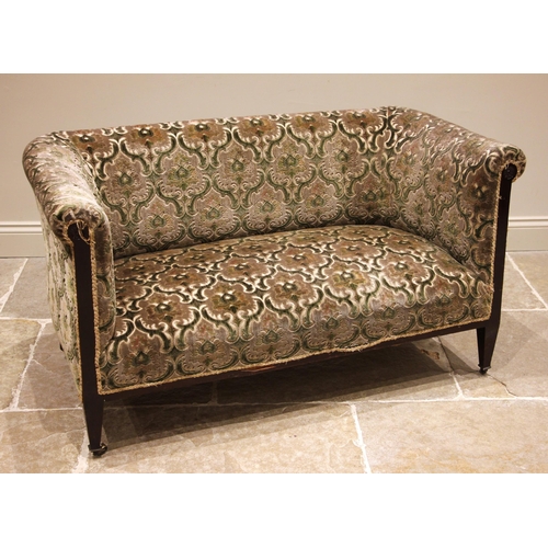 994 - An Edwardian mahogany sofa, in embossed foliate fabric, the padded scroll back rest and arms upon su... 