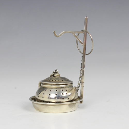 3 - A white metal novelty tea infuser, modelled a pierced teapot with hinged cover, with chain and loop ... 