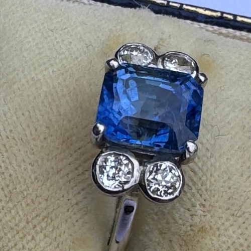 351 - A mid 20th century diamond and sapphire ring, the emerald cut sapphire claw set in white metal, with... 