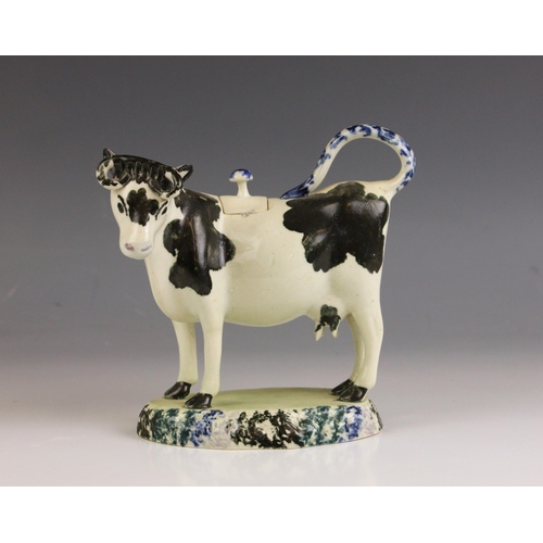 608 - An English pottery cow creamer and cover modelled as a Friesian cow, 19th century, on oval base with... 