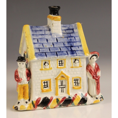 610 - A Yorkshire pottery cottage money box, 19th century, painted in Pratt ware palette, and flanked by t... 