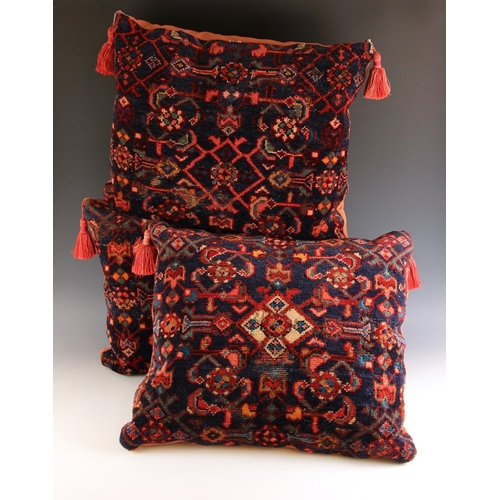 657 - Three Turkish carpet floor cushions, each of geometric design in blue, red and green, tassels to top... 