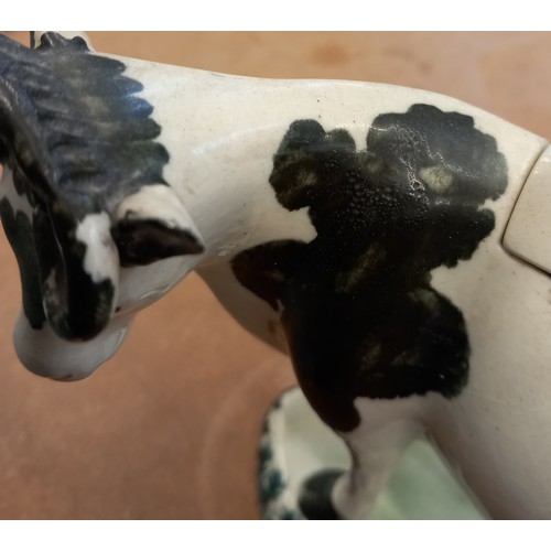 608 - An English pottery cow creamer and cover modelled as a Friesian cow, 19th century, on oval base with... 