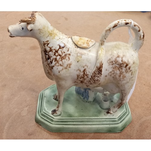 605 - An English pottery cow creamer and cover, circa 1800, Yorkshire or Staffordshire, on a canted and st... 