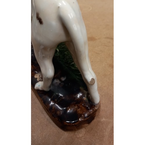 569 - Two French majolica greyhounds, 19th century, each modelled standing against a rough bocage support ... 