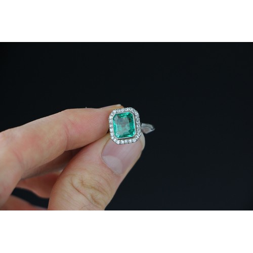 255 - An early 20th century untested emerald and diamond cluster ring, the central emerald cut emerald wit... 