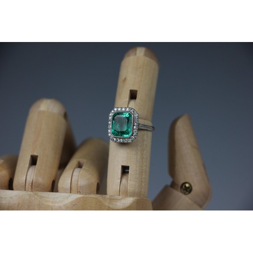 255 - An early 20th century untested emerald and diamond cluster ring, the central emerald cut emerald wit... 