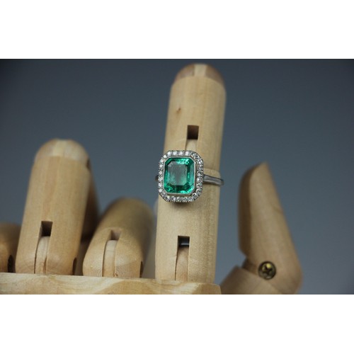 255 - An early 20th century untested emerald and diamond cluster ring, the central emerald cut emerald wit... 