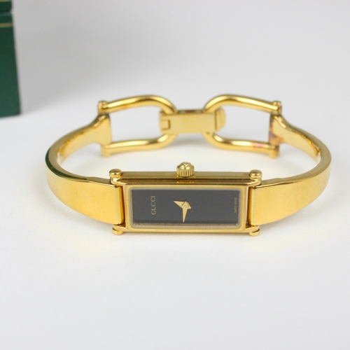 133 - A ladies Gucci wristwatch, the black rectangular dial set to gold coloured plain polished case, stam... 