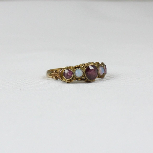 157 - An early 20th century 15ct ring, the central red stone set with opals to each side and further small... 
