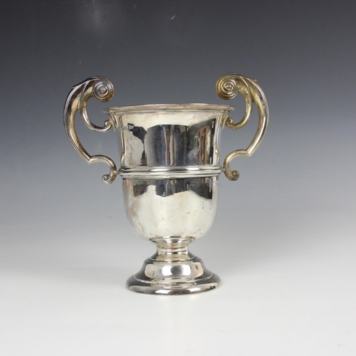 23 - An Edwardian silver twin handled trophy, Walker and Hall, Chester 1906, the scroll handles above pla... 