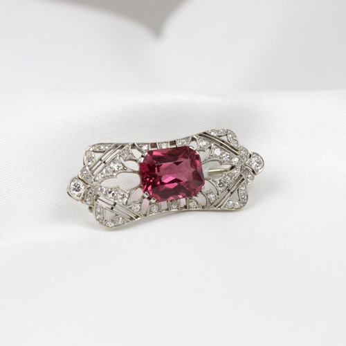 333 - An early 20th century diamond and pink tourmaline brooch, the cushion cut pink tourmaline within a m... 