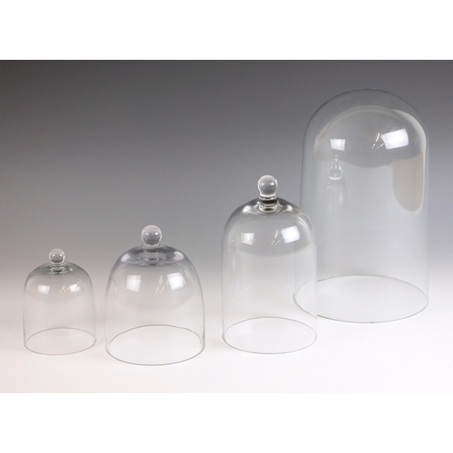 531 - A three graduated glass cloches of small proportions, each of typical form with globular finial, the... 