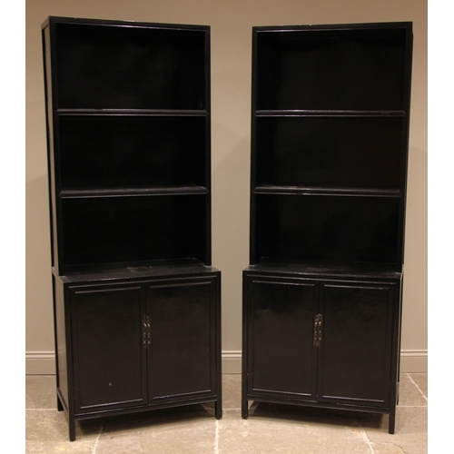 998 - A pair of Japanese influence black painted bookcases, late 20th century, each with two enclosed shel... 