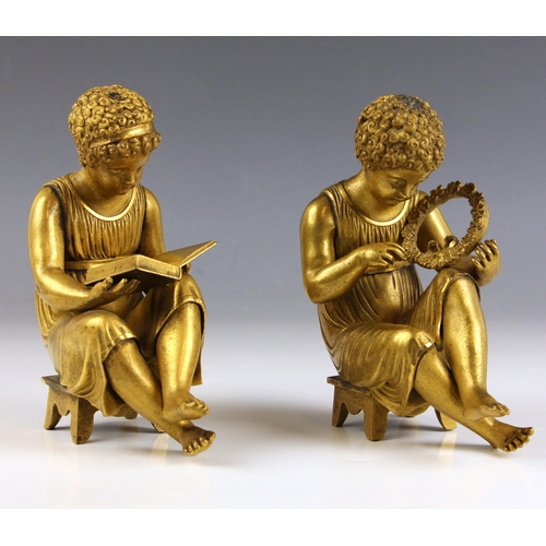 506 - A pair of French gilt bronze putti, 19th century, each modelled seated, one reading a book, the othe... 