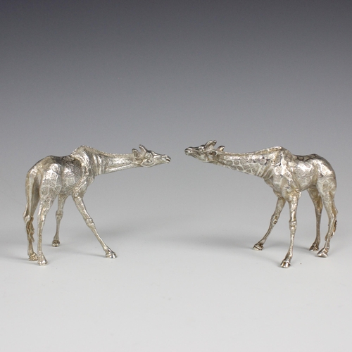 81 - A near pair of Patrick Mavros silver models of giraffes, each modelled standing with realistically c... 