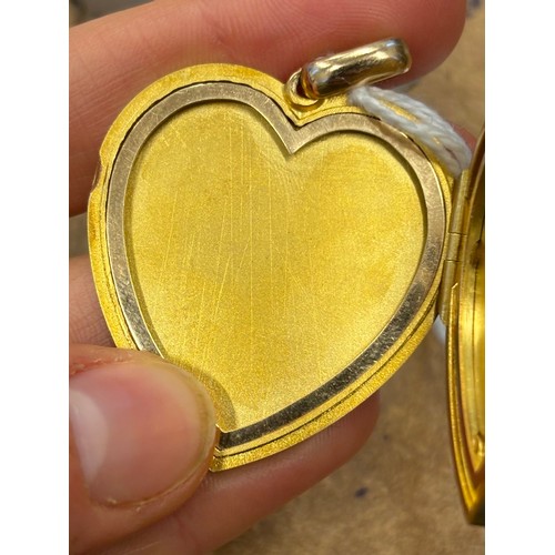 383 - An early 20th century yellow metal heart pendant/locket, the plain polished front with applied fly, ... 