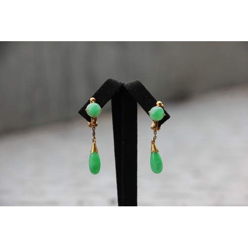 374 - A pair of yellow metal 'jade' drop earrings, the circular cabochon suspending trace link chain and t... 