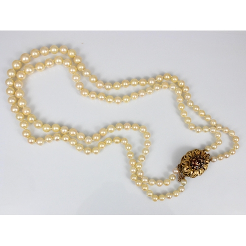 107 - A late 20th century double strand of cultured pearls, of graduated spherical form, with garnet set 9... 