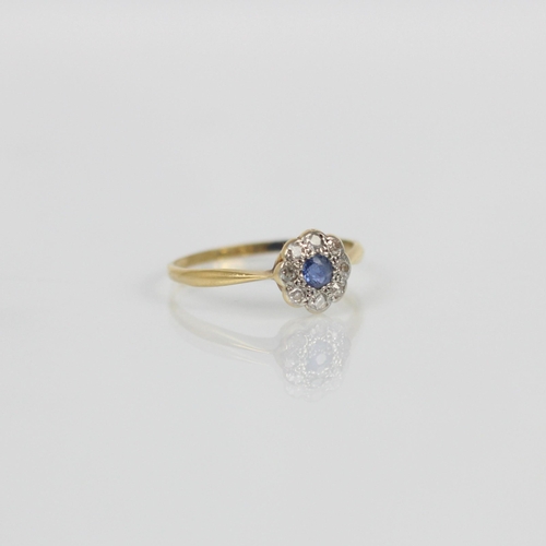 114 - An early 20th century sapphire and diamond cluster ring, the central round cut sapphire within a sur... 